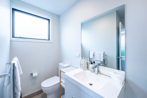 A modern bathroom with a toilet, sink, and window.