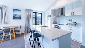 Una cocina moderna con armarios blancos, una isla grande y vistas al exterior.