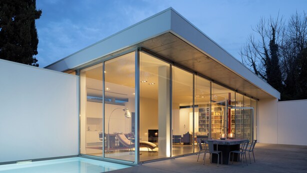 A modern house with a glass-enclosed patio, a pool, and a dining area with chairs and a table. - Casa Briteiros - (Guimarães)
