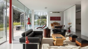 A modern living room with a glass wall, a pool, and a dining area. - Casa Briteiros - (Guimarães)
