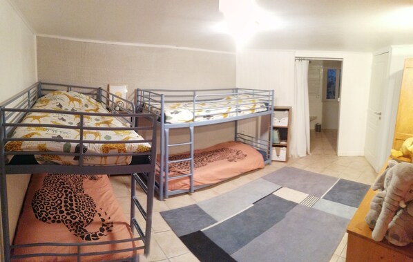 A room with two bunk beds, a small table, and a door leading to a bathroom.
