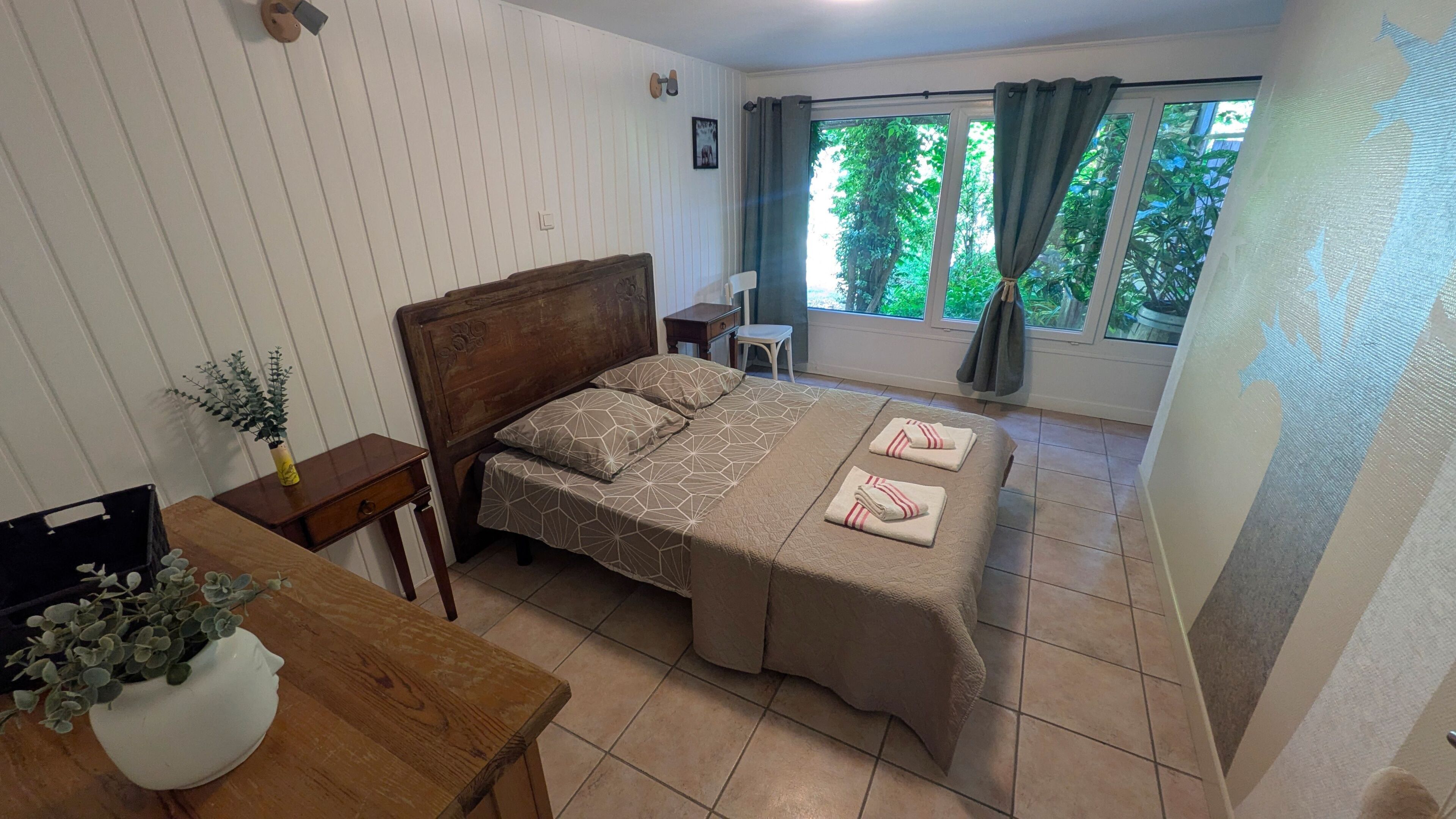 A bedroom with a bed, bedside table, and a window with curtains.