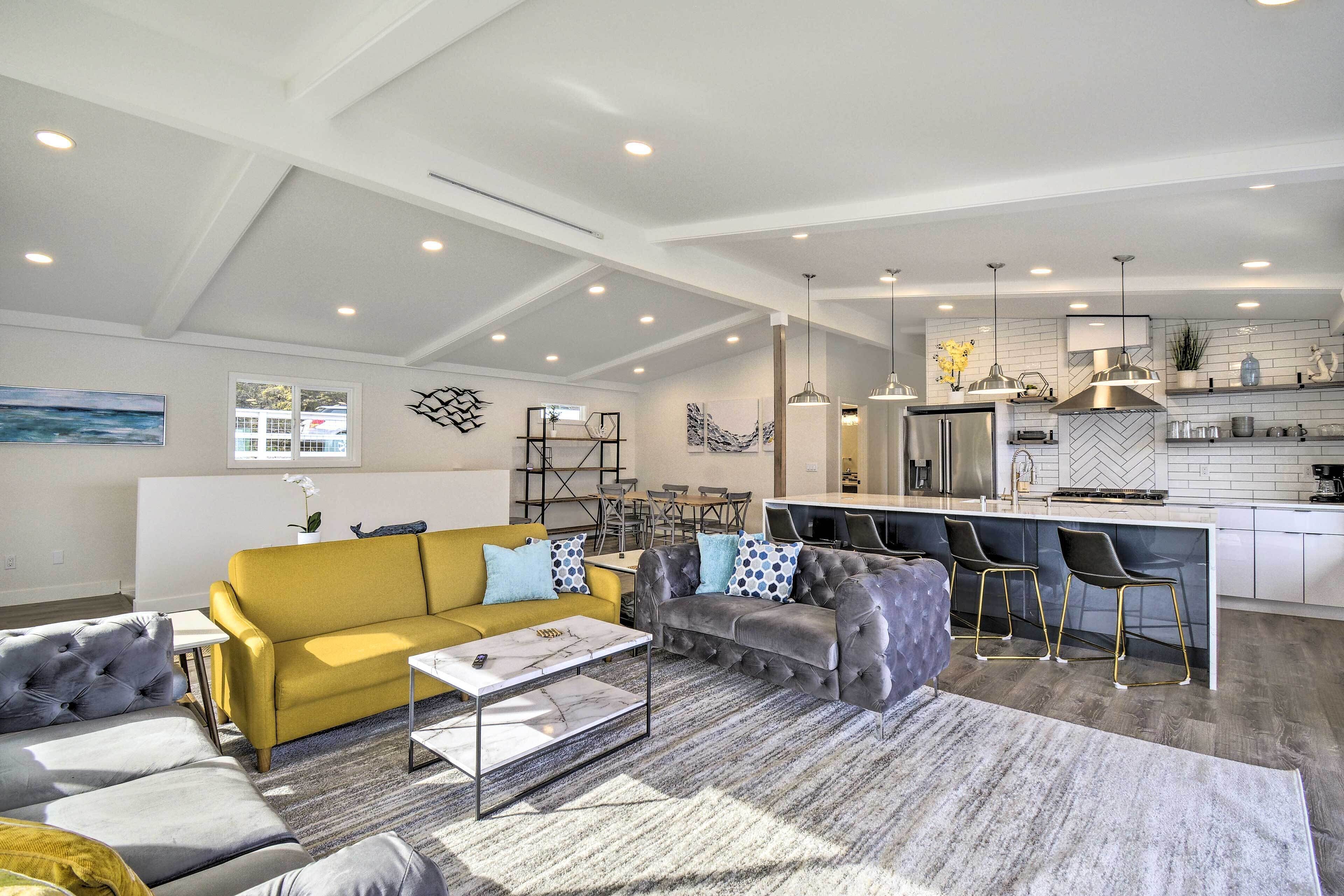 A spacious living area with a yellow sofa, grey armchairs, and a coffee table.