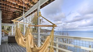 Una hamaca en una terraza de madera con vista al mar y a las montañas.