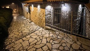 A stone building with a tiled roof, a satellite dish, and a gated entrance. - Dandy Villas Dimitsana a family home in a quaint historic neighborhood  (Dimitsana)