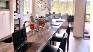 A modern kitchen with a long island, a clock, and a view of the outdoors. - Mustang Mountain Retreat in Bison Ridge! (Show Low)