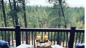 A deck with two blue chairs and a small table with a tray of food and drinks. - Mustang Mountain Retreat in Bison Ridge! (Show Low)