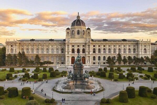 A large, historic building with a central courtyard and a statue.