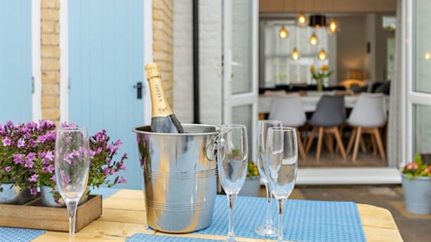 An outdoor dining area with a table set for two, a champagne bottle, and two glasses. - 4 Bedroom Seaside House, Beach 220m with Free Parking (Sidmouth)