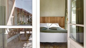 Une chambre à coucher avec une tête de lit en bois, un lit avec une literie blanche et une fenêtre avec des rideaux.