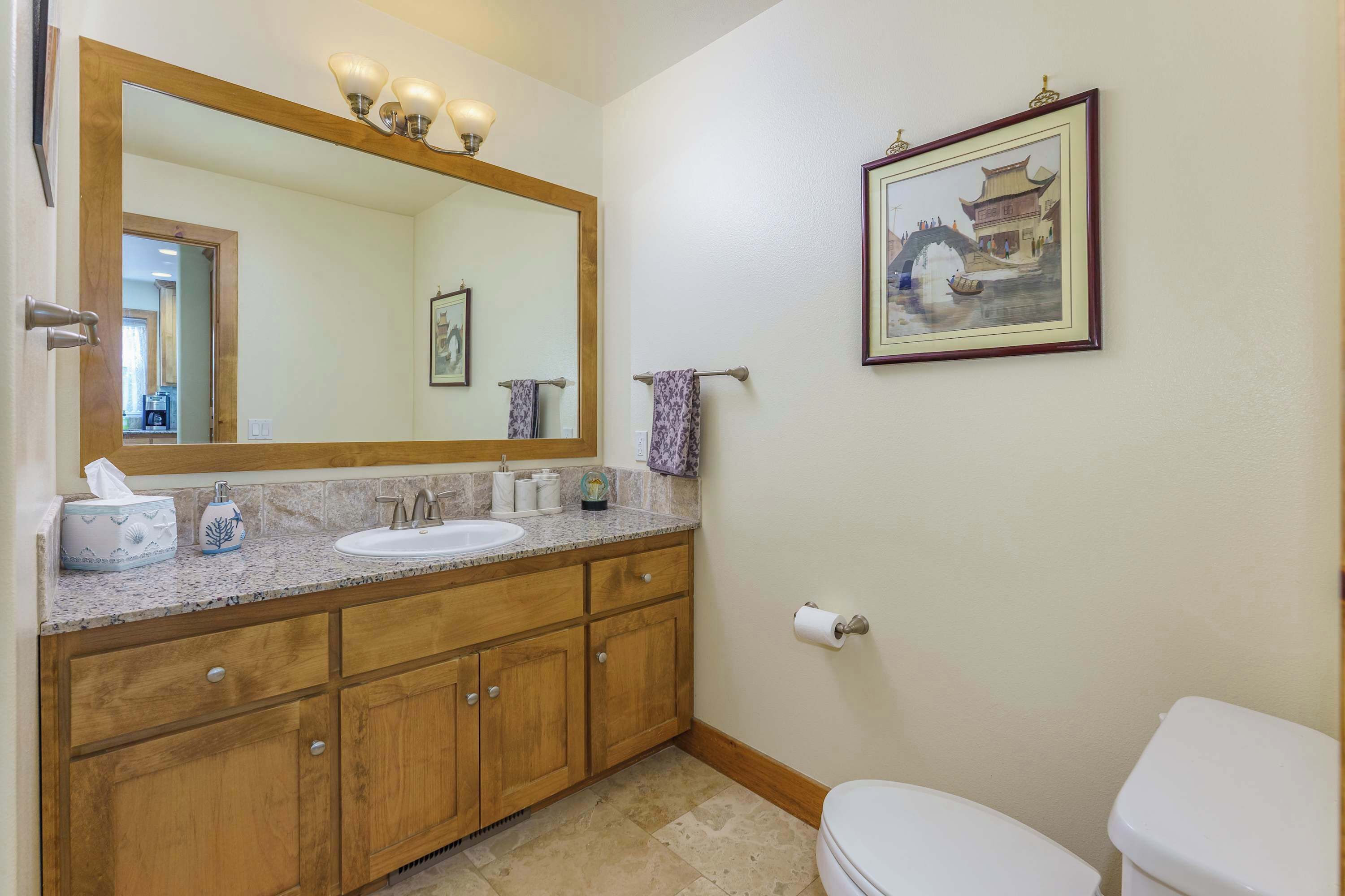 Un baño con tocador de madera, un espejo grande, un lavabo y un inodoro.