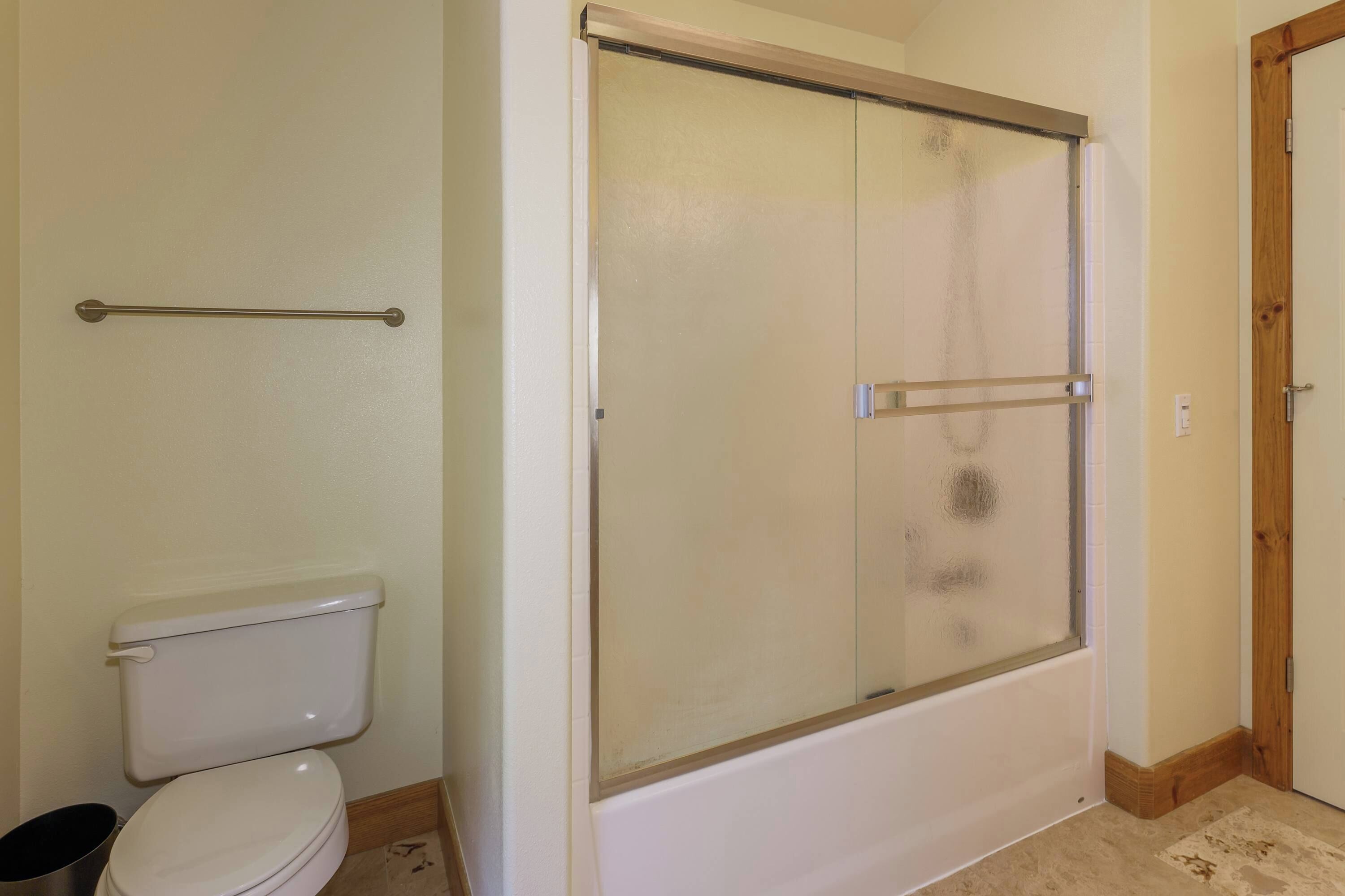 A bathroom with a toilet, a shower enclosure, and a wooden door.