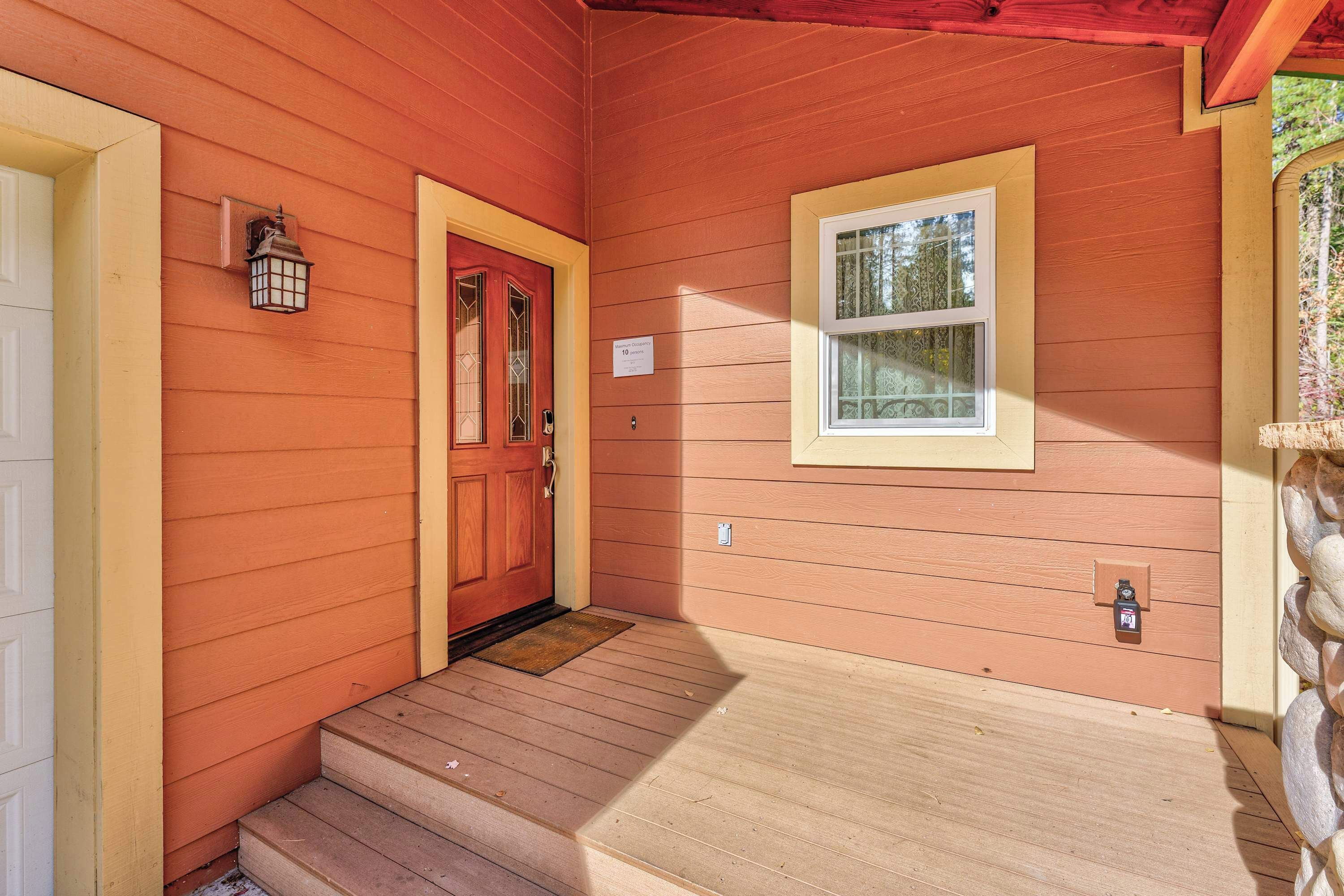 A wooden house with a red door, a small window, and a porch with steps.