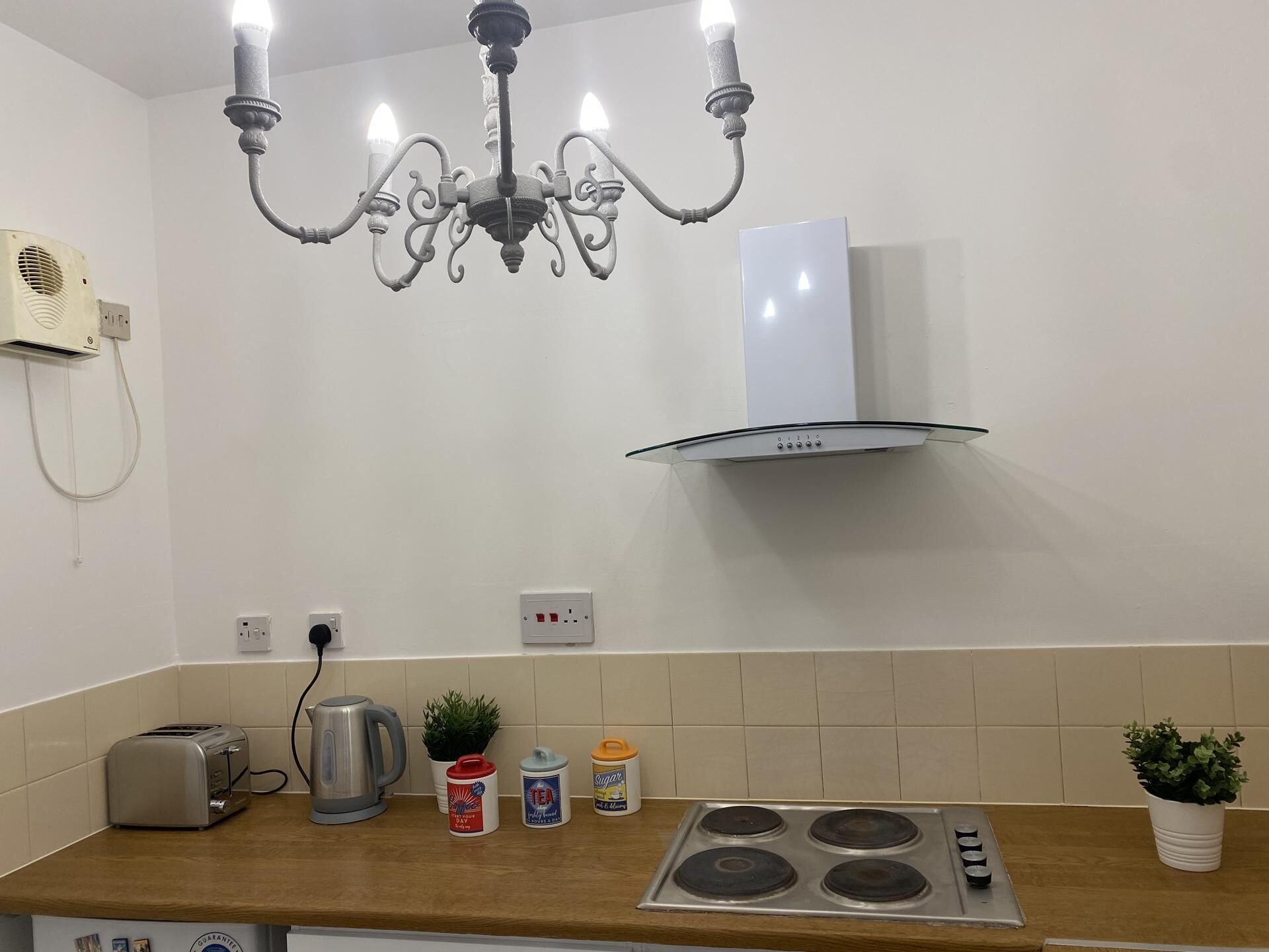 Una cucina con un lampadario, una cappa aspirante, un tostapane, un bollitore e diversi elettrodomestici.