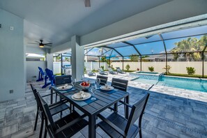 Un patio con piscina, mobiliario exterior y un espacio de comedor techado.