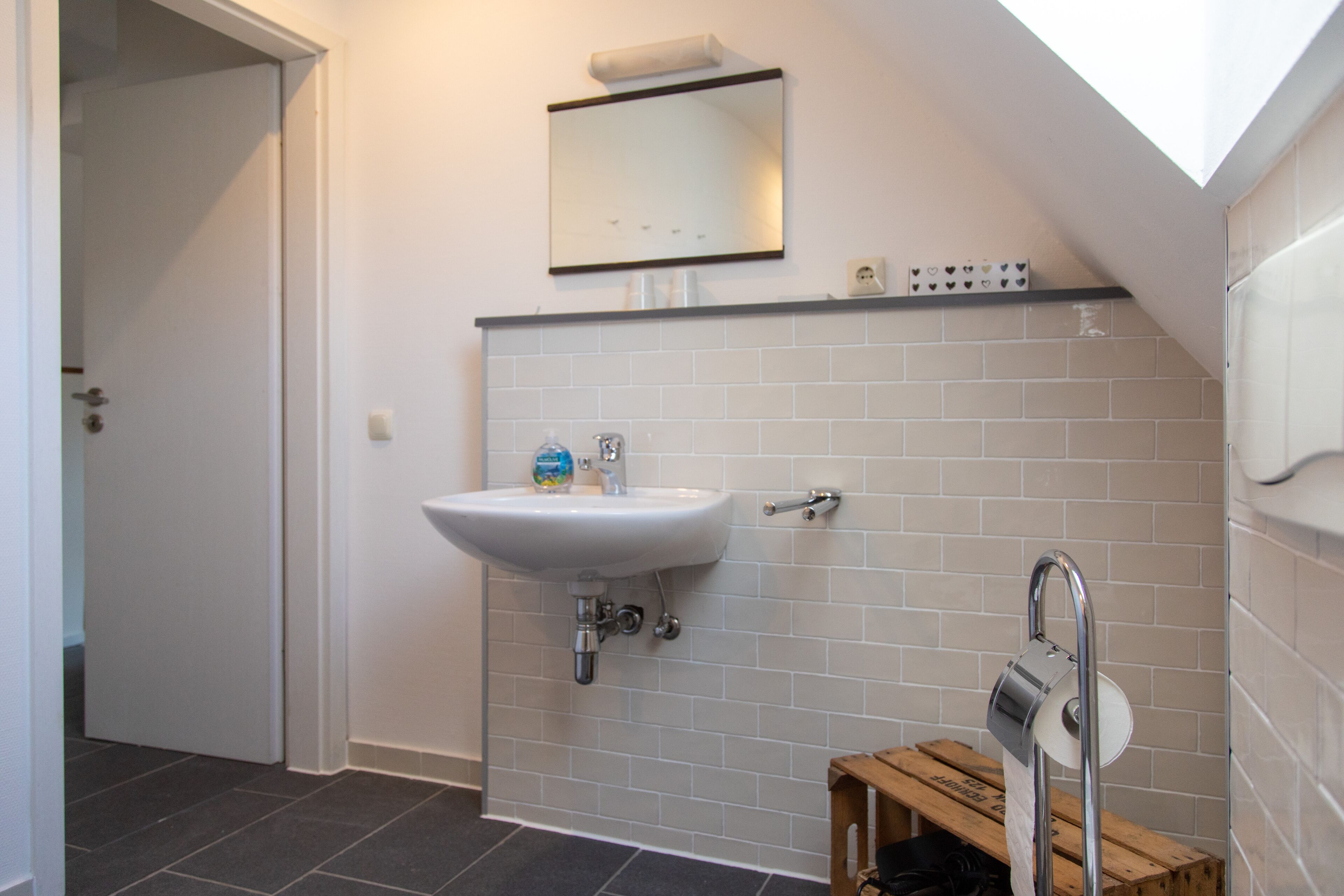 A bathroom with a white sink, a mirror, and a towel rack.