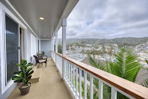 A balcony with a view of a town and hills.