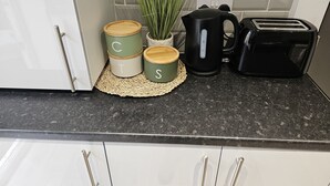 A kitchen counter with three storage containers, a potted plant, a coffee maker, and a toaster.