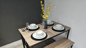 A dining table set with plates, bowls, cutlery, and a vase with yellow flowers.