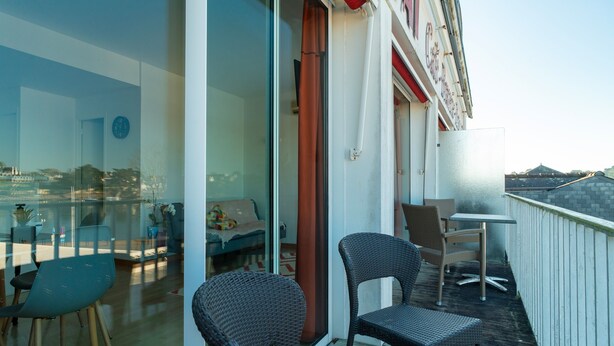 A balcony with wicker chairs and a small table, overlooking a cityscape. - France - Appt pour 4 proche plage (Benodet)