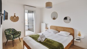 A modern hotel room with a large bed, a chair, a mirror, and a view of the outside. - Le Rochenoire - Appt proche plage (Dinard)