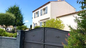 A two-story house with a tiled roof and a black gate. - Room Carrington  (Roquebrune-sur-Argens)
