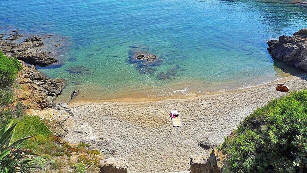 A coastal beach with clear water, rocky shoreline, and a small beach chair. - Room Carrington  (Roquebrune-sur-Argens)
