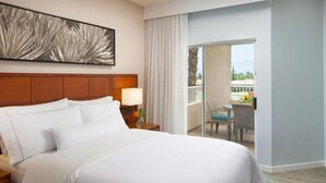 A hotel room with a large bed, a nightstand with a lamp, a view of the balcony, and a painting on the wall. - The Westin Mission Hills Resort Villas, Palm Springs (Rancho Mirage)