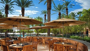 An outdoor patio area with wooden tables and chairs, surrounded by palm trees and umbrellas. - The Westin Mission Hills Resort Villas, Palm Springs (Rancho Mirage)