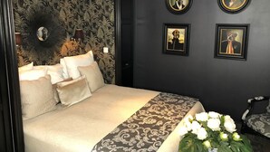 Ein Schlafzimmer mit einem großen Bett, einem verzierten Kopfteil und drei gerahmten Bildern an der Wand.