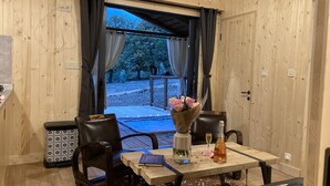 A wooden interior with a table set for two, a bouquet of flowers, and a bottle of water. - Cabane Insolite et Nature Avec Jacuzzi et Piscine Prés Carcassonne Occitanie (VILLARZEL DU RAZES)