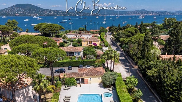 A residential property with a swimming pool, surrounded by lush greenery and a view of the sea with boats. - Renovated apartment Brise Marine II near the beach and close to St-Tropez (Gassin)