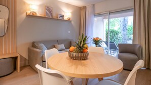 A modern living room with a round wooden table, white chairs, a sofa, and a window with curtains. - Renovated apartment Brise Marine II near the beach and close to St-Tropez (Gassin)