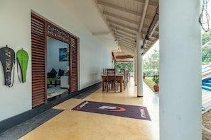 A hotel corridor with a wooden ceiling, a reception desk, and a dining area with chairs and tables. - Tropical Paradise Villa in Talpe (Unawatuna)