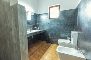 A modern bathroom with a wooden floor, a large mirror, a sink, a toilet, and a bathtub. - Tropical Paradise Villa in Talpe (Unawatuna)