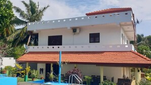 A two-story building with a swimming pool, a covered patio, and a red-tiled roof. - Tropical Paradise Villa in Talpe (Unawatuna)