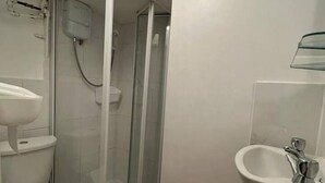 A bathroom with a toilet, a sink, and a glass-enclosed shower. - Studio Flat in Lovely Alexandra Palace, London (London)