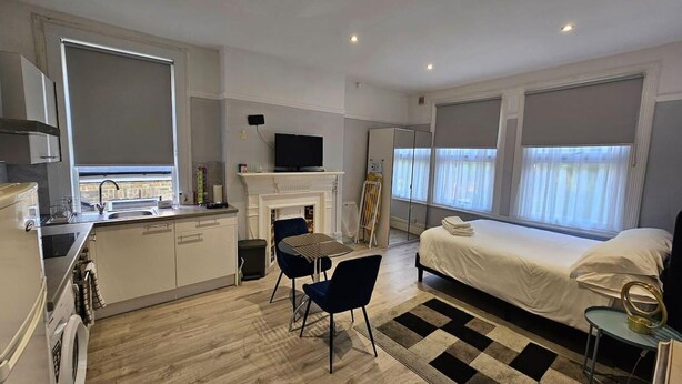 A compact hotel room with a kitchenette, a dining area, a bed, and a bathroom. - Studio Flat in Lovely Alexandra Palace, London (London)