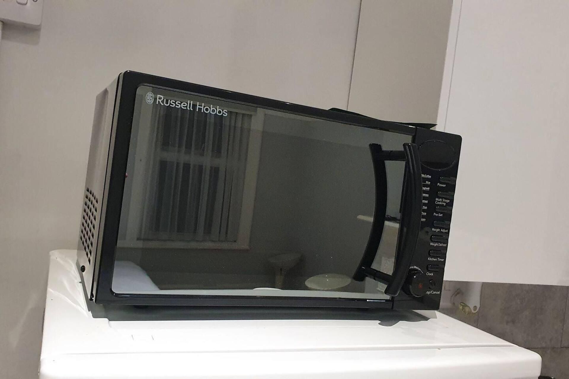 A black Russell Hobbs microwave oven on a white countertop.