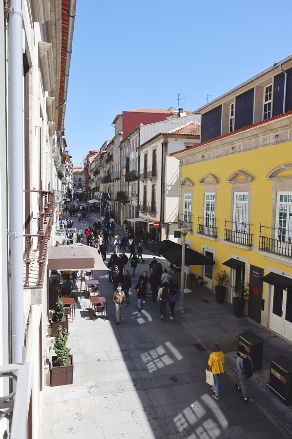 A narrow street with buildings on either side, outdoor seating, and a clear sky. - RIBEIRA FLORES 59 Downtown Apartments (Porto)