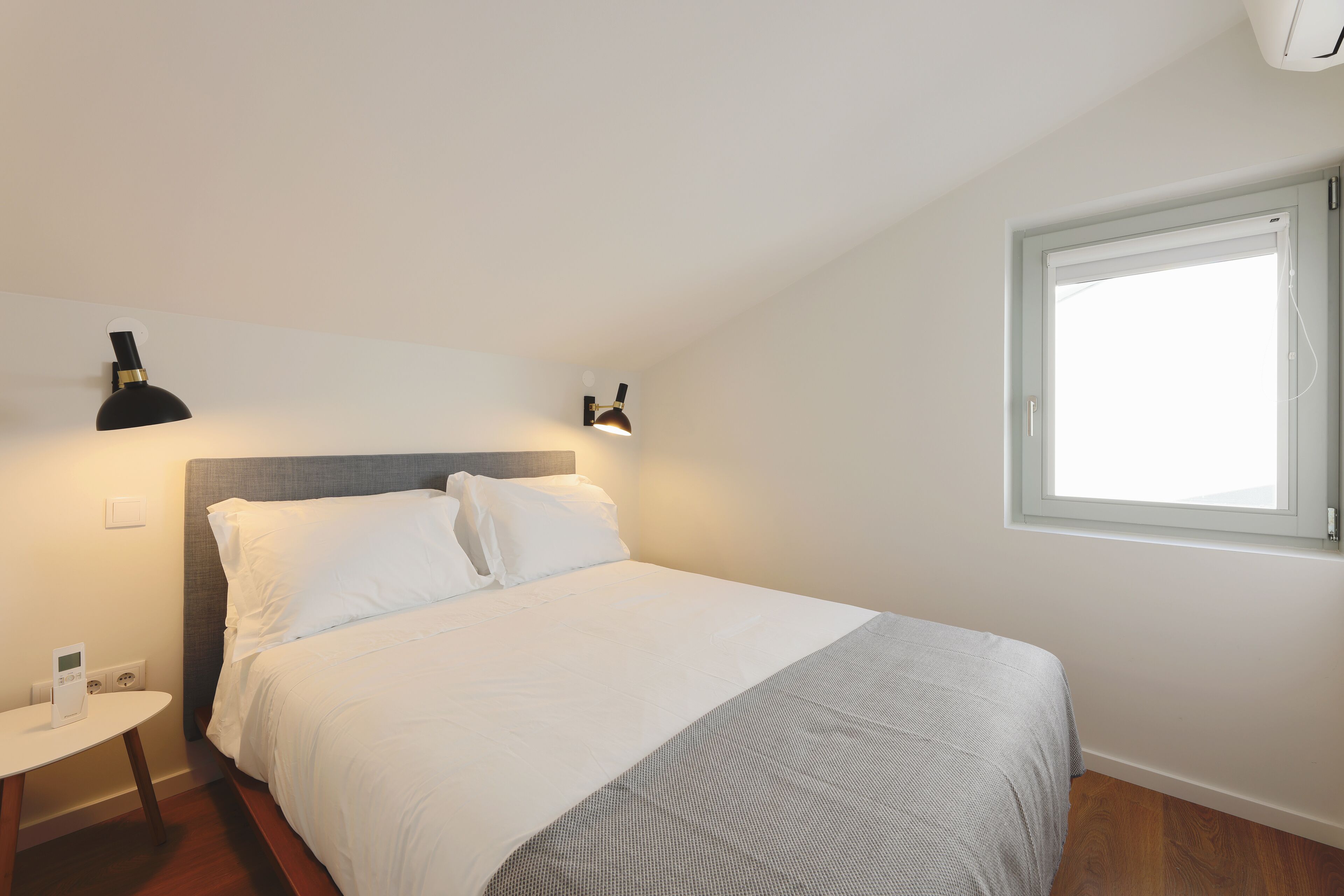Ein Hotelzimmer mit Bett, Nachttisch, Lampe und Fenster.