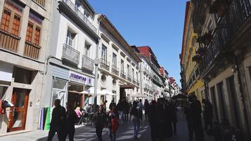 A pedestrian street lined with multi-story buildings, some with balconies and outdoor seating.
