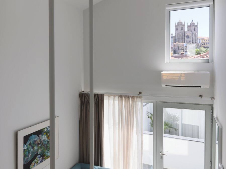 Un salon moderne avec un canapé bleu, un tableau encadré au mur et une vue sur le paysage urbain par la fenêtre.