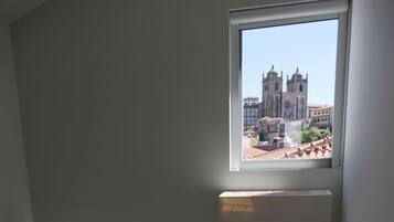 A room with a view of a cathedral through a window, a sofa, and an air conditioning unit.