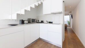 A modern kitchen with white cabinets, a microwave, a coffee maker, and a sink. - RIBEIRA FLORES 59 Downtown Apartments (Porto)