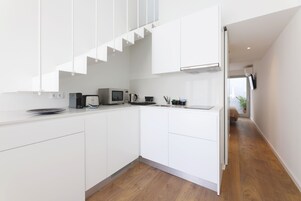 A modern kitchen with white cabinets, a microwave, a coffee maker, and a sink.