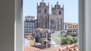 A view through a window of a historic building with a clock tower, adjacent buildings, and a tiled roof. - RIBEIRA FLORES 59 Downtown Apartments (Porto)