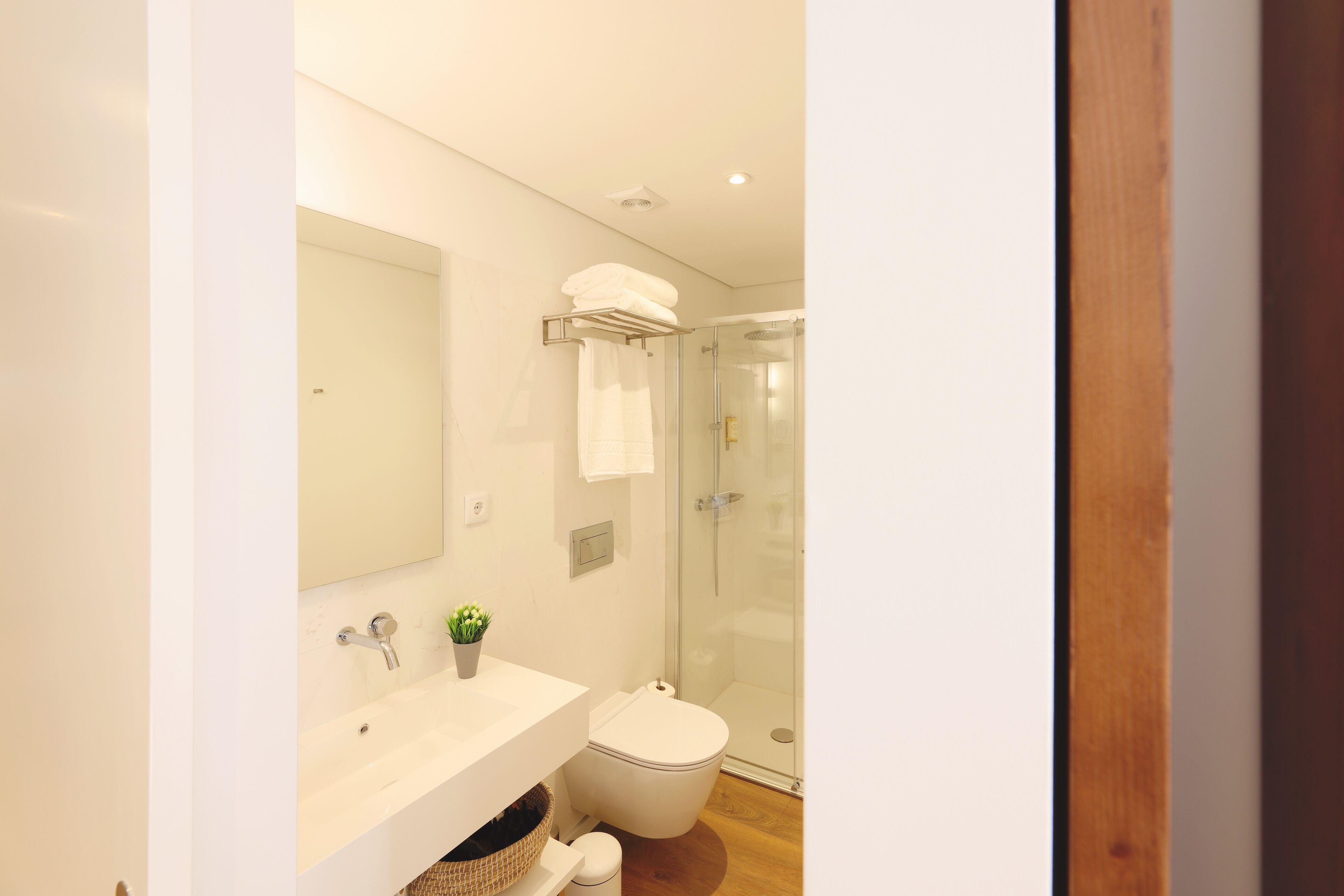 A modern bathroom with a glass shower enclosure, a white sink, and a toilet.