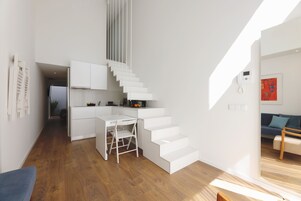 A modern interior with a staircase, a kitchen area, and a seating area.