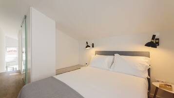 A bedroom with a bed, bedside table, and wall-mounted lamp.
